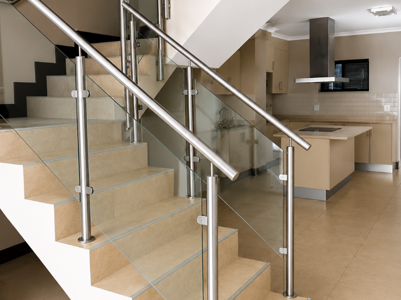 Open plan living area featuring a modern tiled staircase with glass balustrade and a contemporary kitchen with built-in cabinetry and stainless steel appliances.