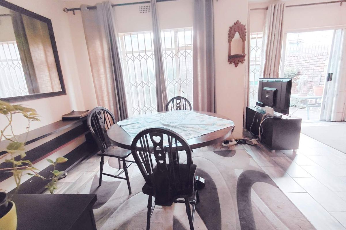 A living area featuring tiled flooring and sliding glass doors with security gates, providing access to an outdoor patio space.
