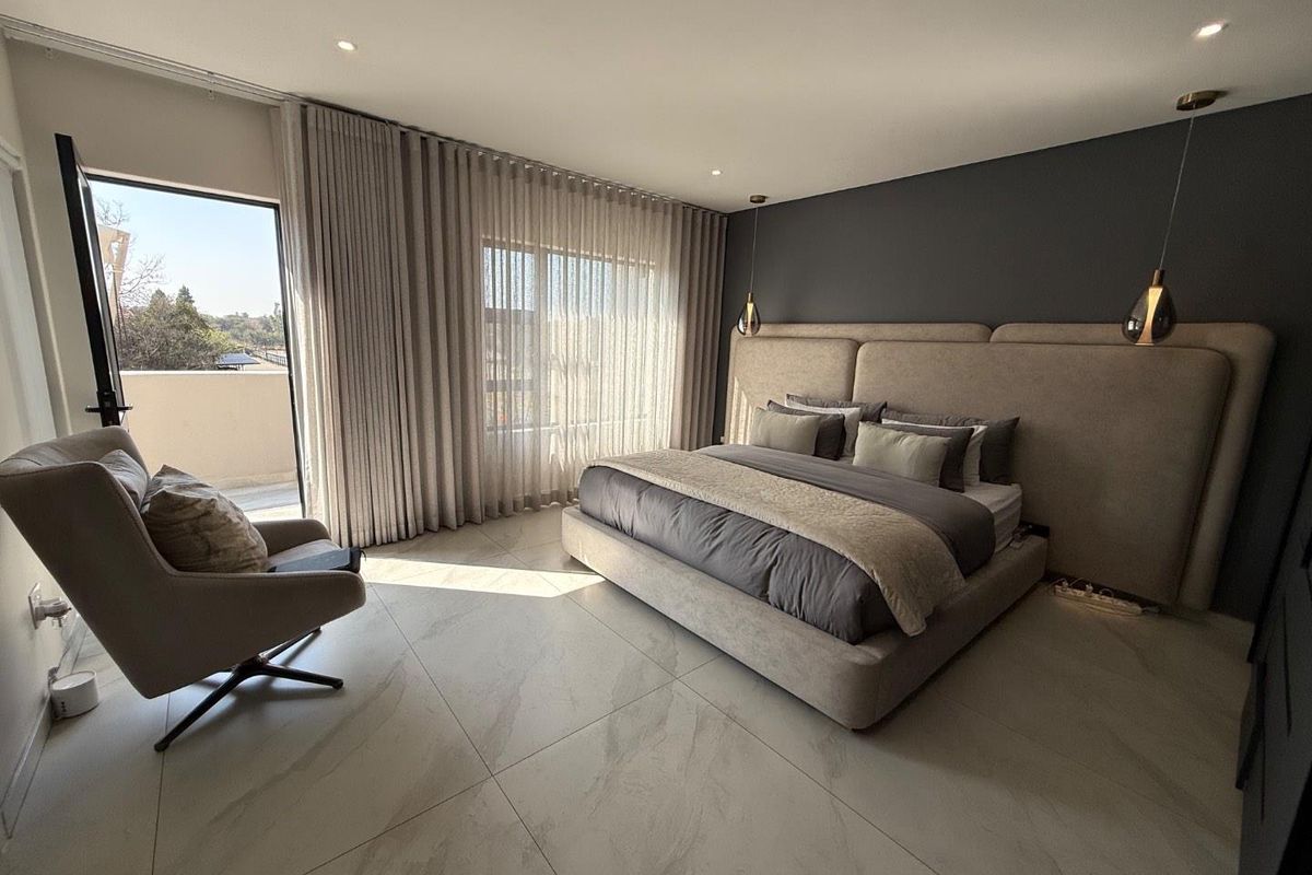 Modern bedroom featuring large format floor tiles, recessed ceiling lighting, and direct access to a private balcony through a glass door.