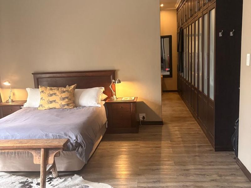 Spacious bedroom featuring extensive built-in dark wood cabinetry, modern laminate flooring, and recessed ceiling lighting.