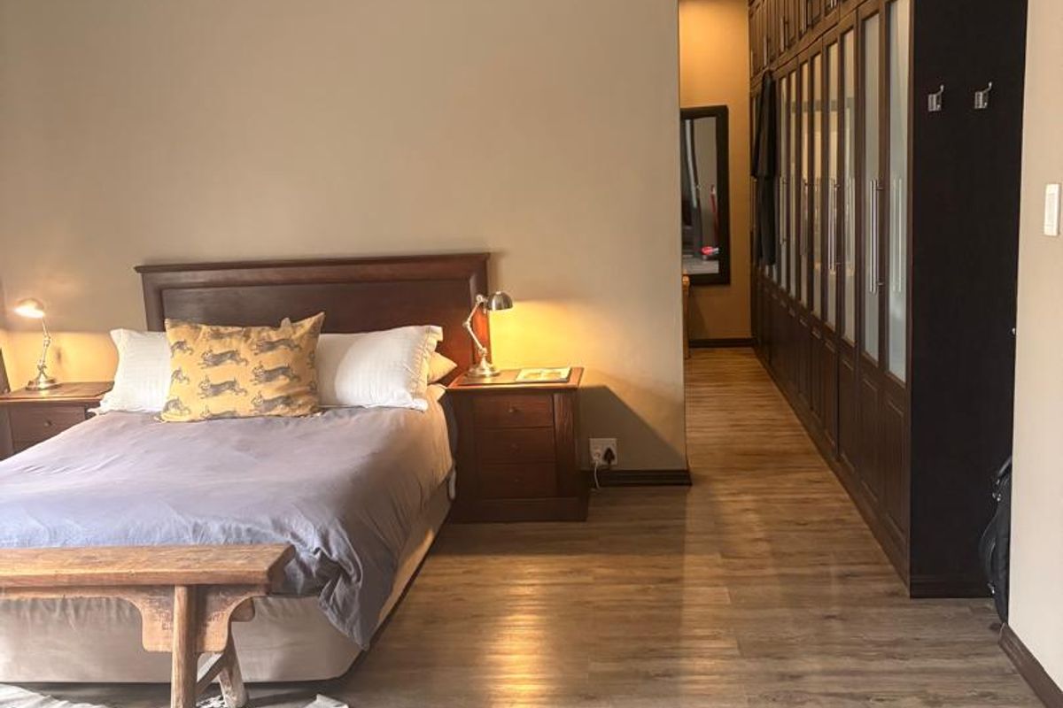 Spacious bedroom featuring extensive built-in dark wood cabinetry, modern laminate flooring, and recessed ceiling lighting.