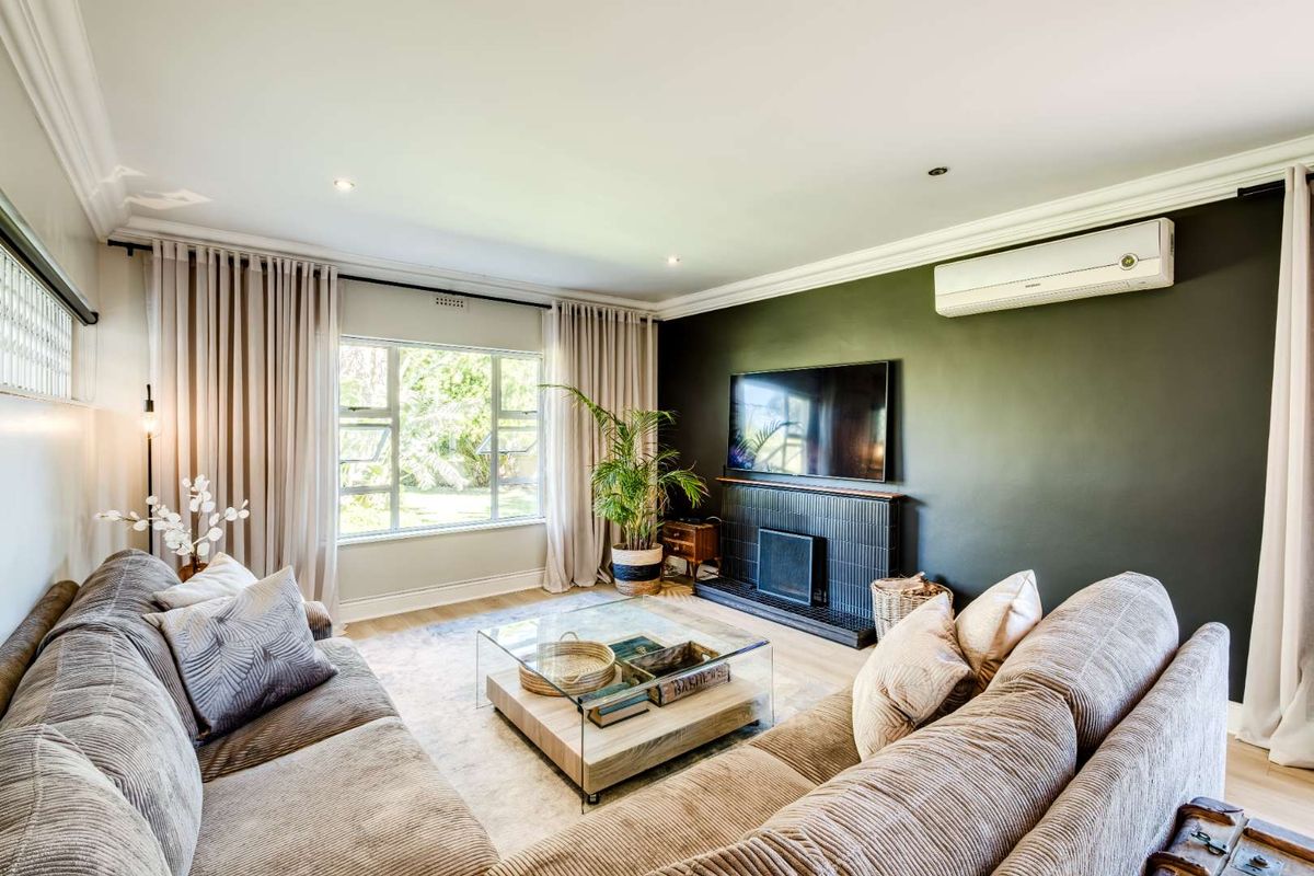A well-appointed living room featuring a dark accent wall, a built-in fireplace, and a wall-mounted air conditioning unit.