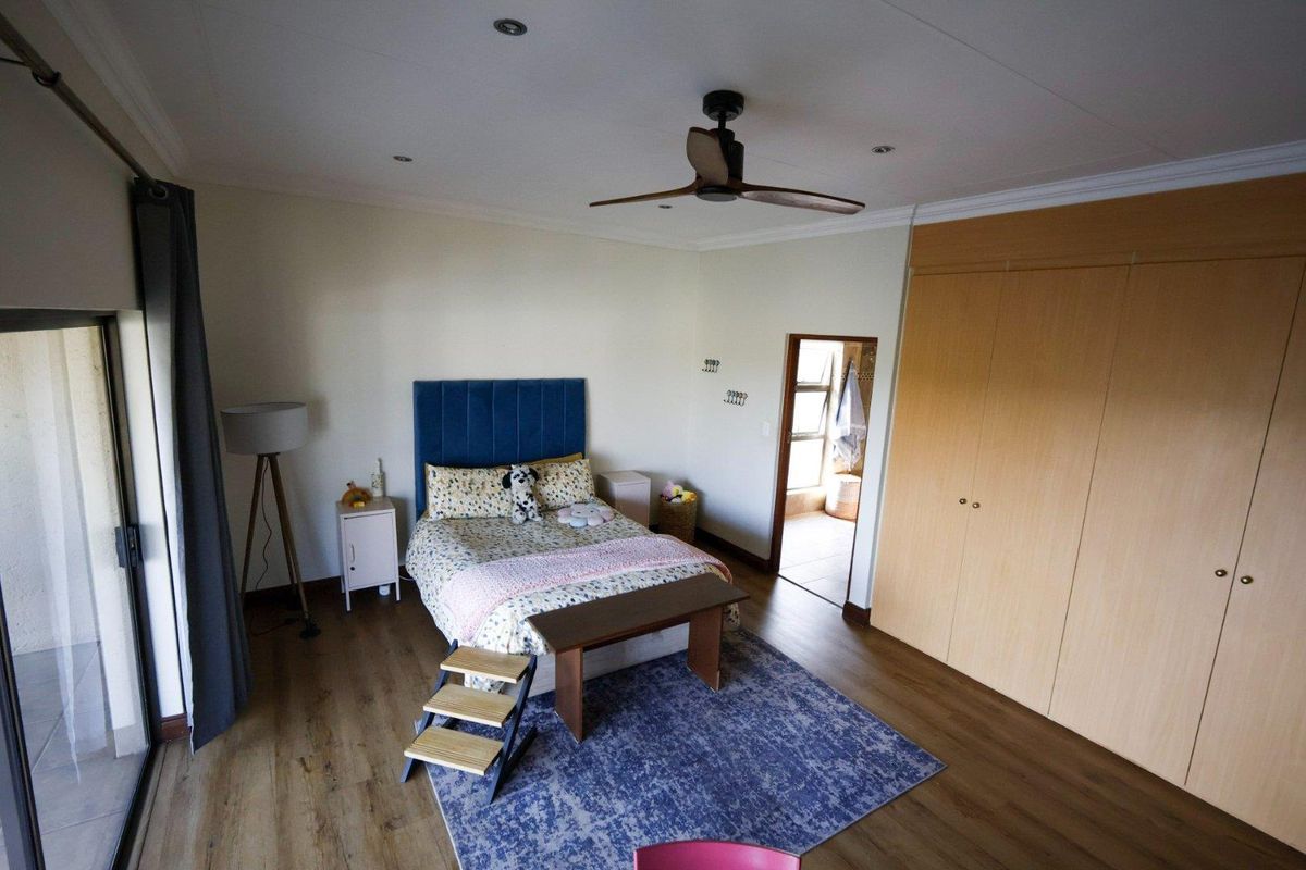 Spacious bedroom featuring wood-look flooring, built-in wooden cupboards, a ceiling fan, and sliding door access to an outdoor area.