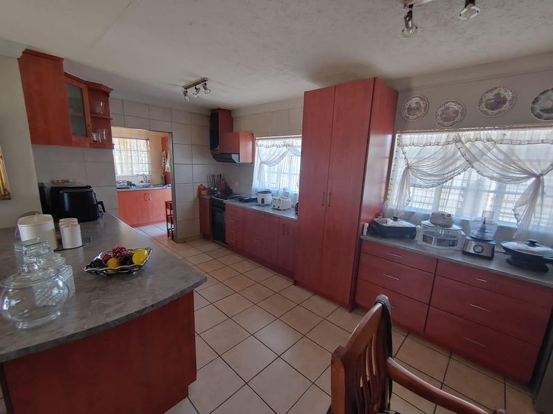 Spacious kitchen featuring extensive built-in cabinetry, laminate countertops, ceramic tile flooring, and a functional layout with an adjoining scullery area.