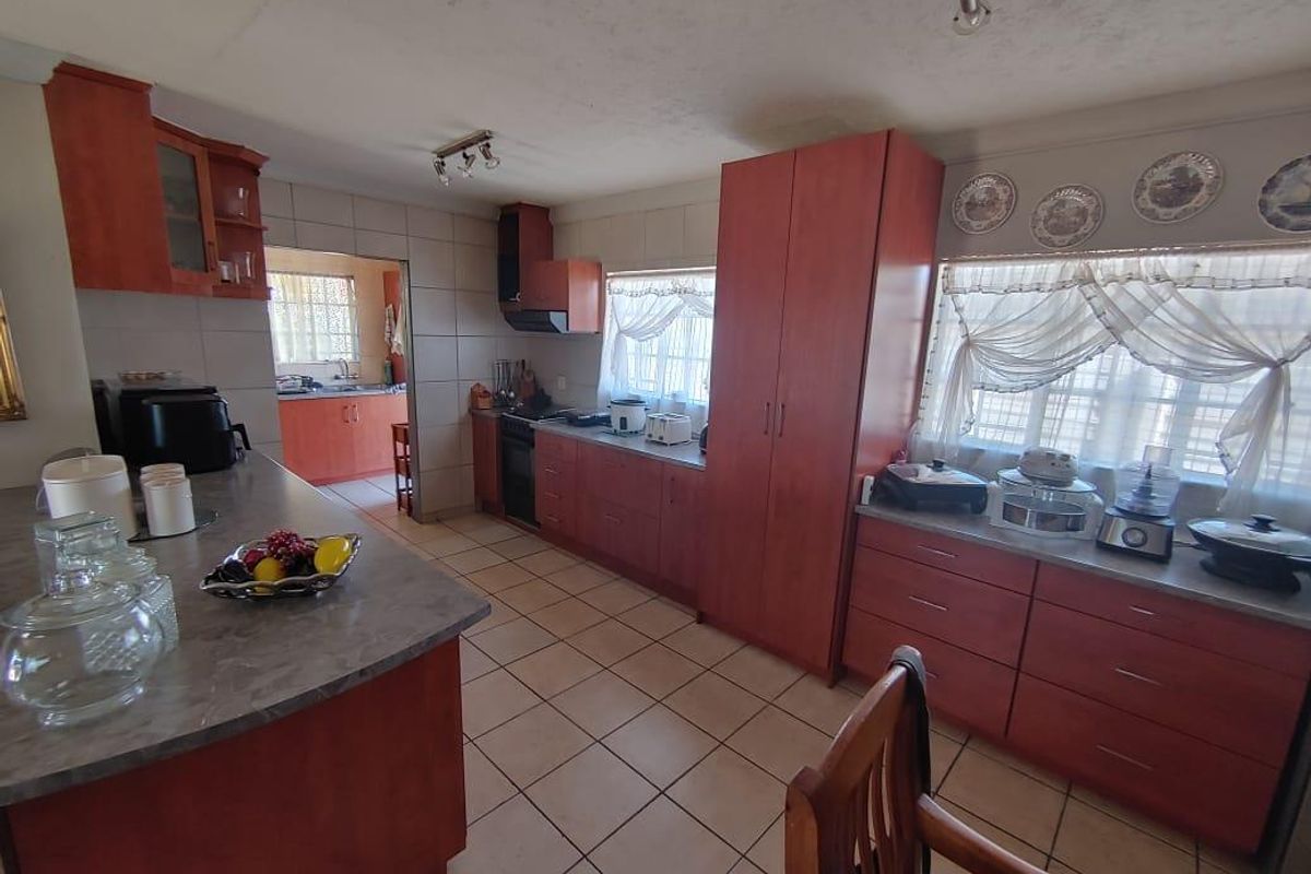 Spacious kitchen featuring extensive built-in cabinetry, laminate countertops, ceramic tile flooring, and a functional layout with an adjoining scullery area.