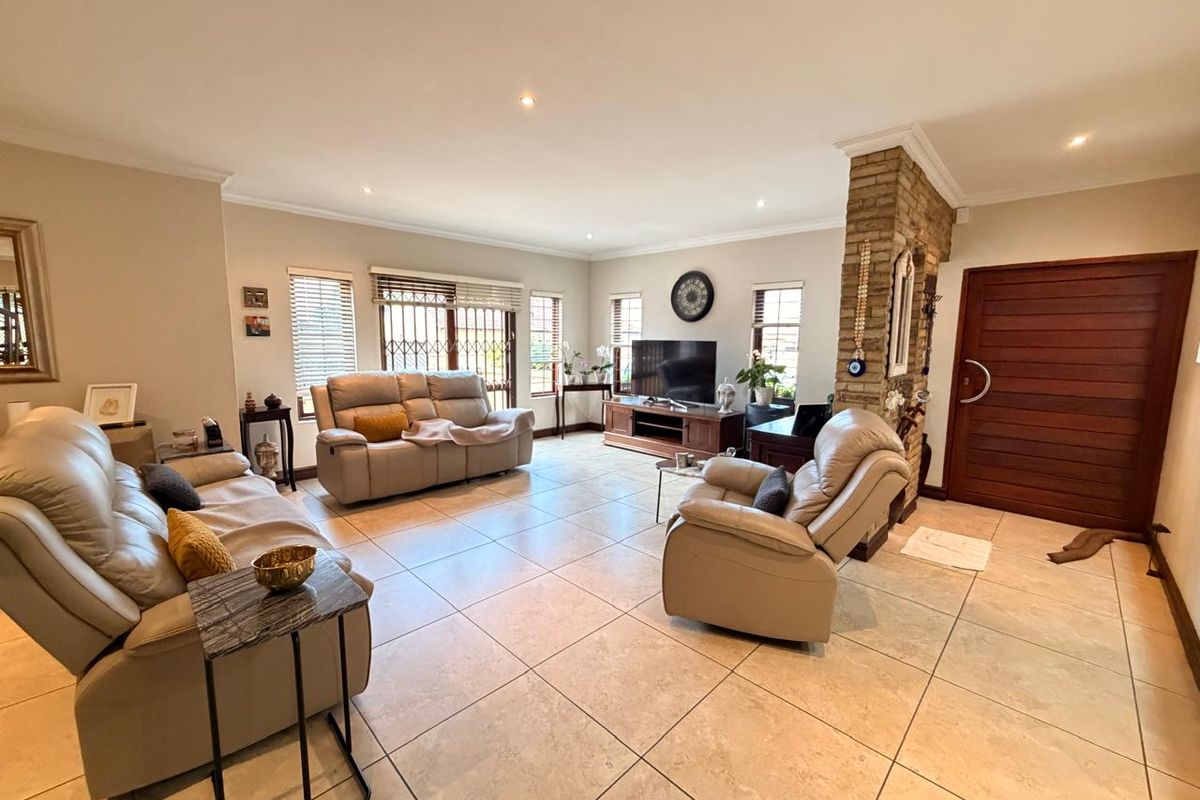 Spacious living room featuring large floor tiles, an exposed brick feature pillar, recessed lighting, and direct access to the outdoor area.