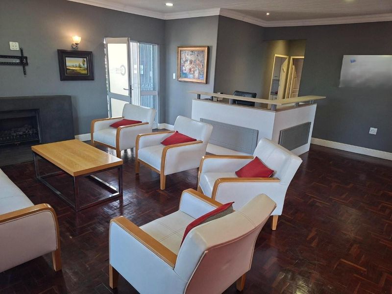 A spacious living area featuring dark parquet flooring, a built-in fireplace, and a reception-style counter, suitable for a home office or lounge.