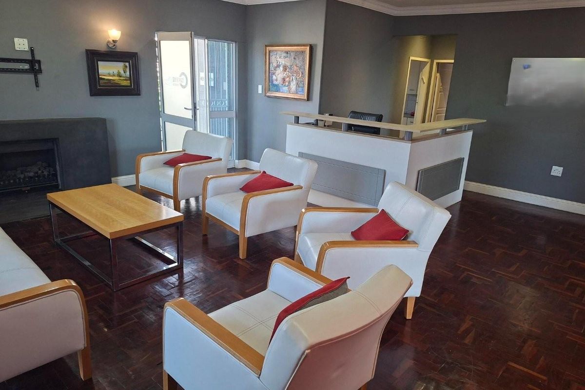 A spacious living area featuring dark parquet flooring, a built-in fireplace, and a reception-style counter, suitable for a home office or lounge.