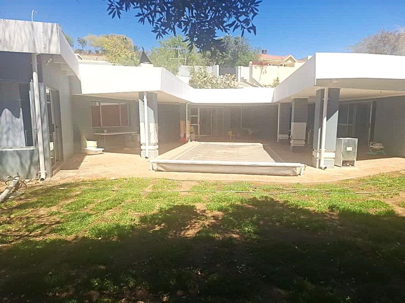 Rear view of the property featuring a covered patio area, swimming pool, and direct access to the garden through sliding glass doors.
