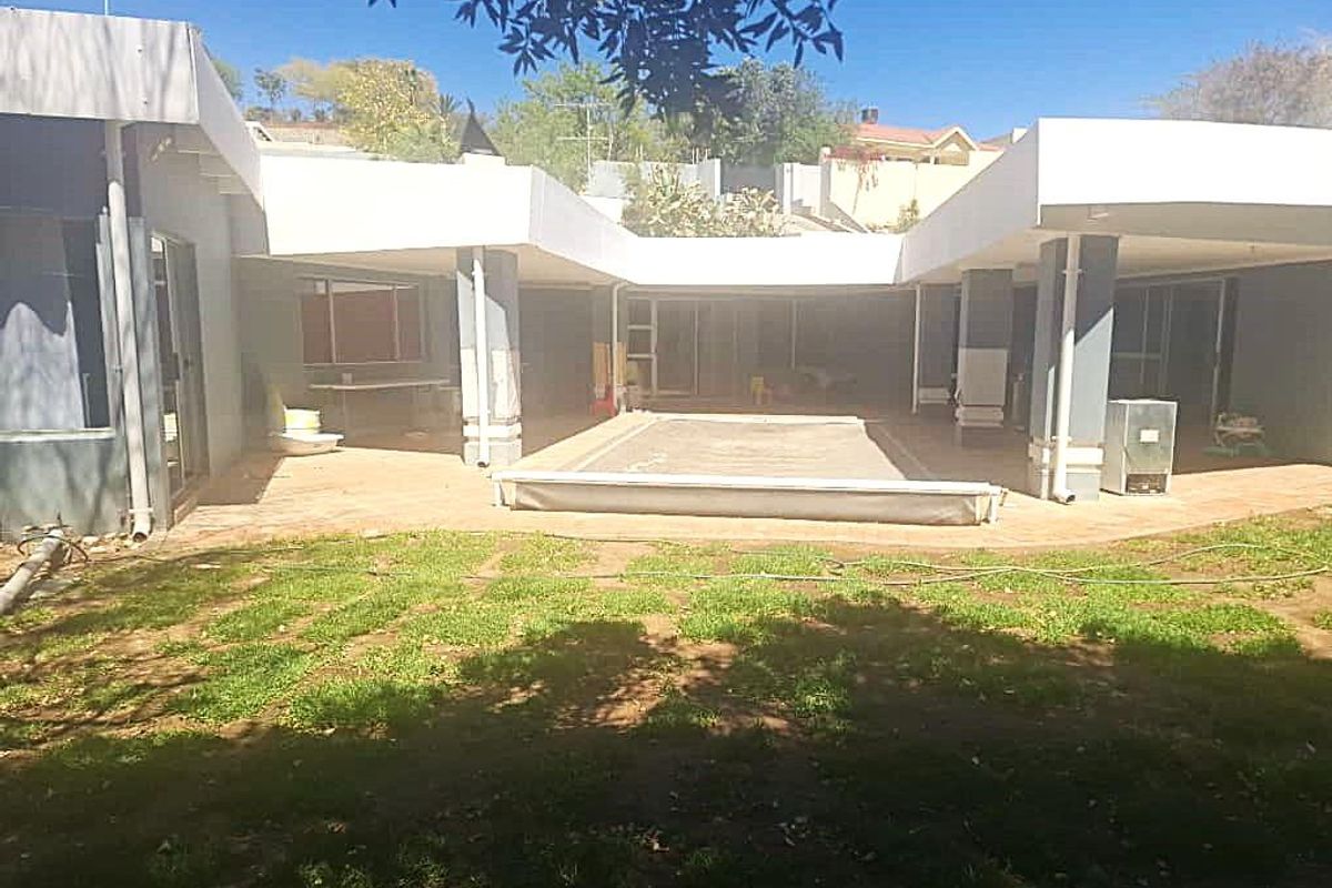 Rear view of the property featuring a covered patio area, swimming pool, and direct access to the garden through sliding glass doors.