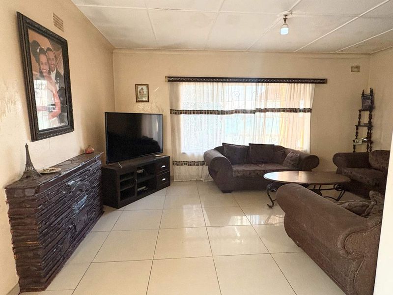 A living room featuring tiled flooring and a tiled ceiling, offering a functional space with potential for cosmetic updates.
