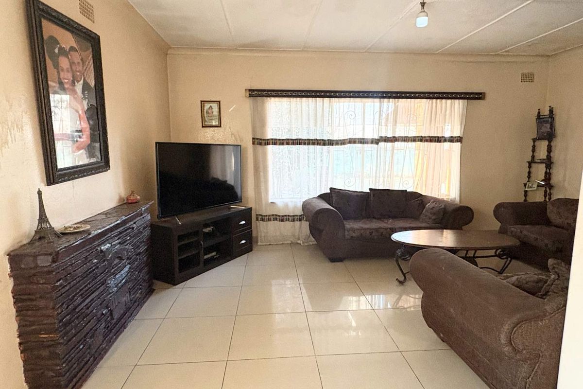 A living room featuring tiled flooring and a tiled ceiling, offering a functional space with potential for cosmetic updates.