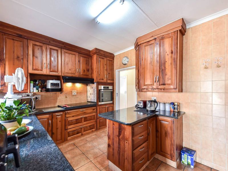 A functional kitchen featuring solid wood cabinetry, granite countertops, built-in oven, and ceramic tiling throughout.