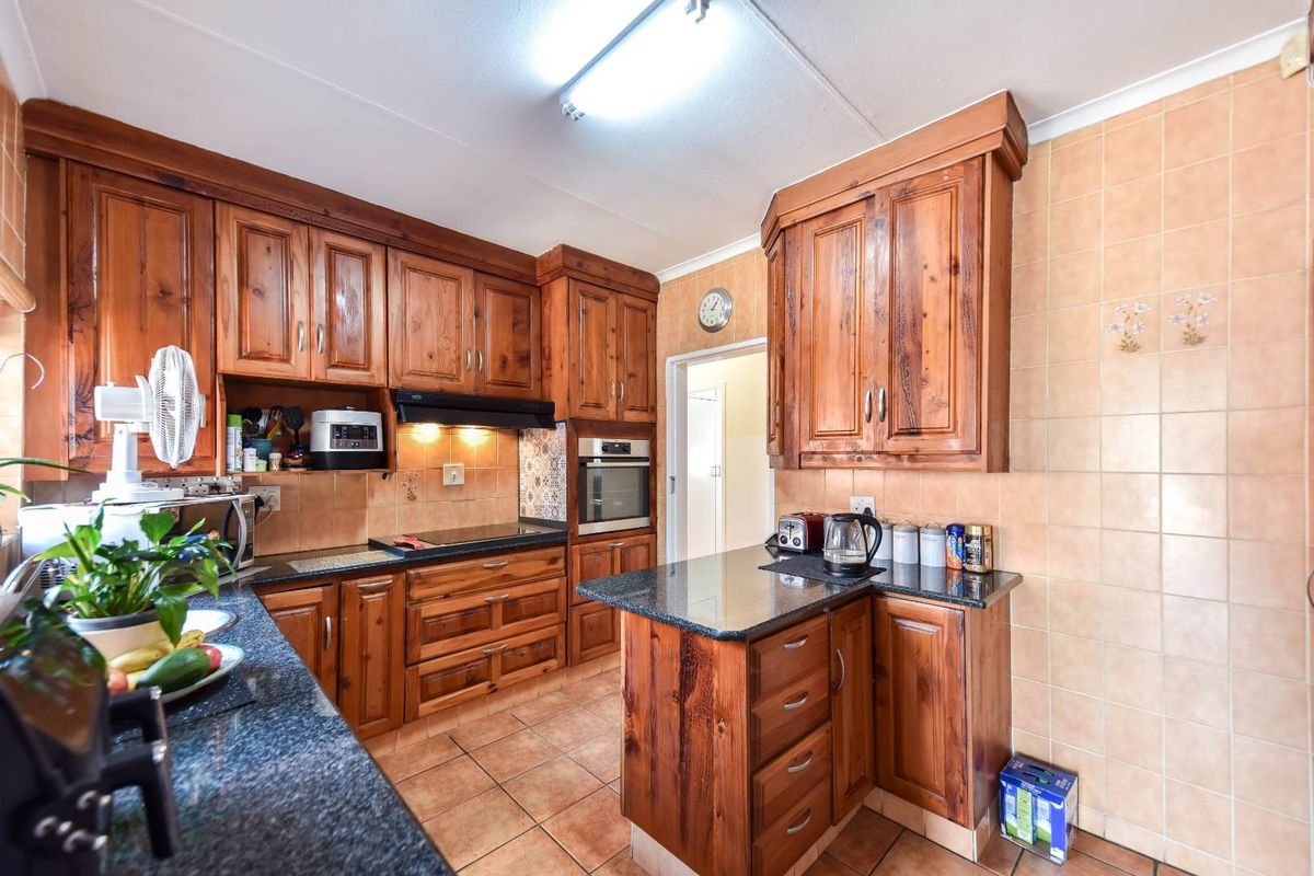 A functional kitchen featuring solid wood cabinetry, granite countertops, built-in oven, and ceramic tiling throughout.