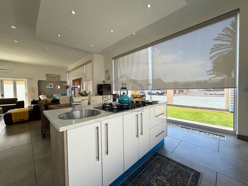 Modern open-plan living area featuring a sleek kitchen island with a built-in gas hob and sink, flowing seamlessly into the adjacent lounge space.
