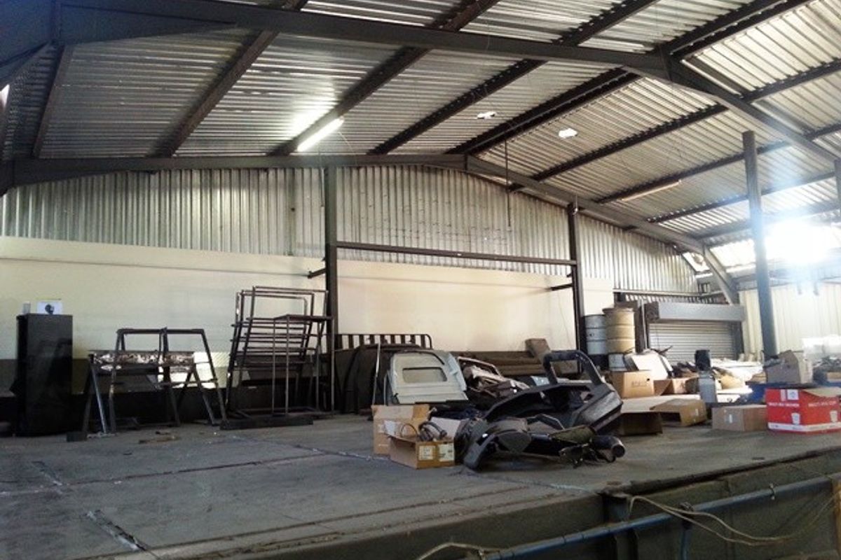 Spacious industrial utility area featuring a high corrugated metal roof, exposed steel structural beams, and a raised concrete platform suitable for storage or operations.
