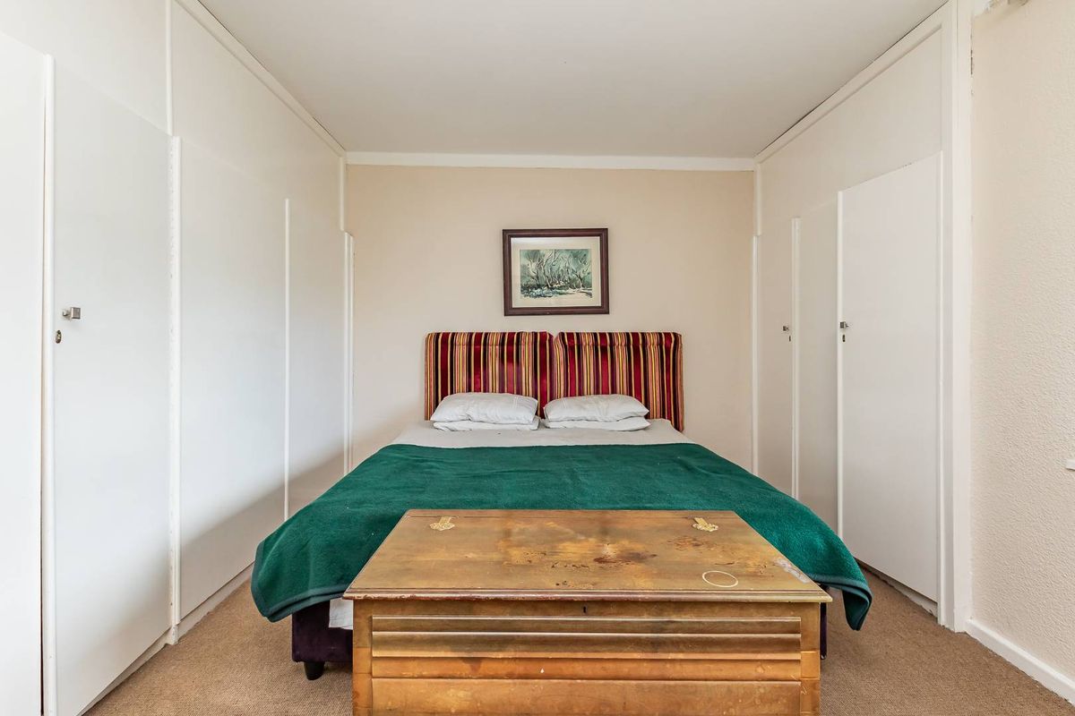A bedroom featuring extensive built-in floor-to-ceiling storage cupboards on both sides and neutral wall finishes.