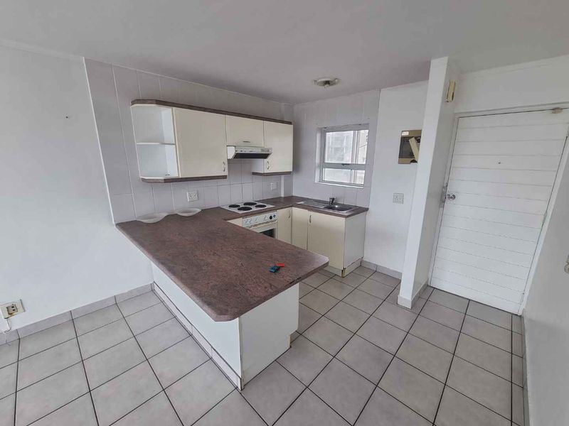 A functional kitchen featuring built-in cabinetry, laminate countertops, an electric hob, and tiled flooring, offering a clean and practical layout.