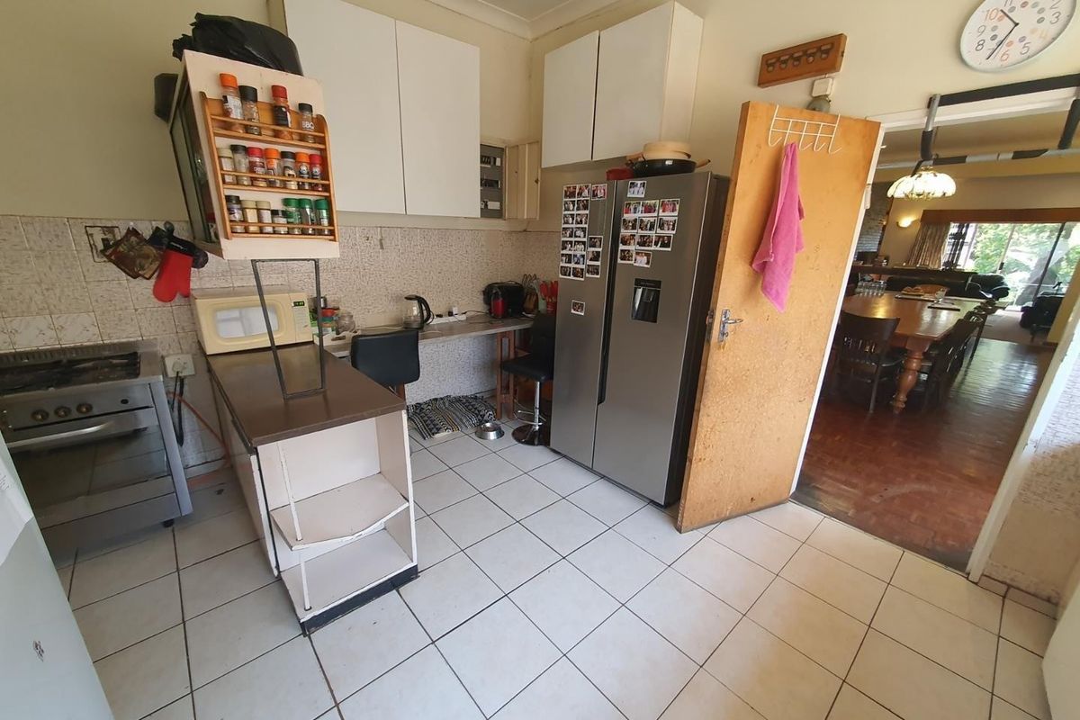 A functional kitchen area featuring white cabinetry, tiled flooring, and a built-in stove, with an open-plan flow leading into the adjacent dining space.