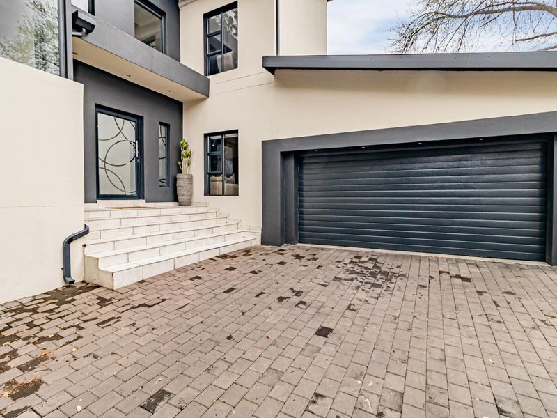 Modern front facade featuring a paved driveway, double garage, and tiled entrance steps leading to a contemporary front door.