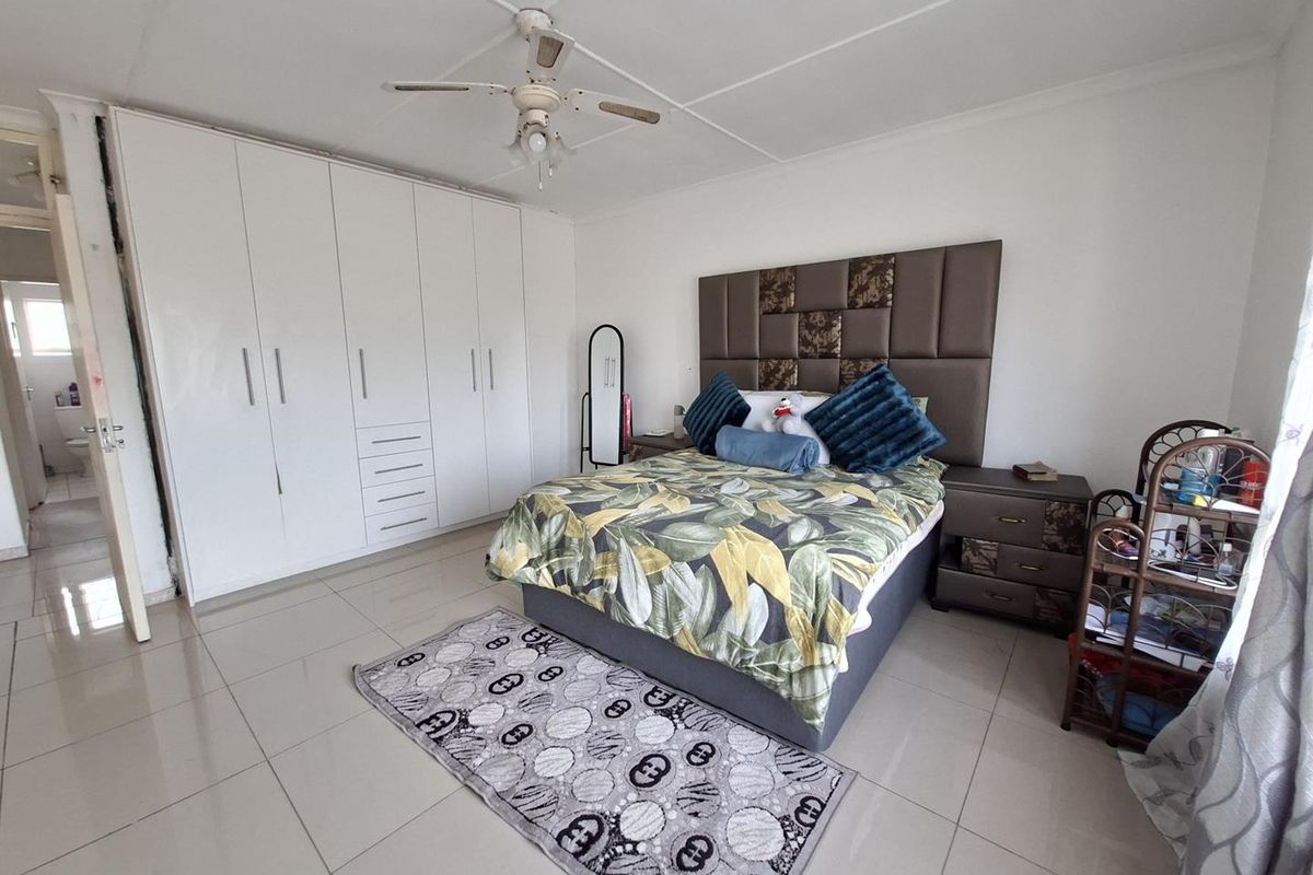 Spacious bedroom featuring large built-in cupboards, tiled flooring, and a ceiling fan, offering a functional and well-maintained living space.