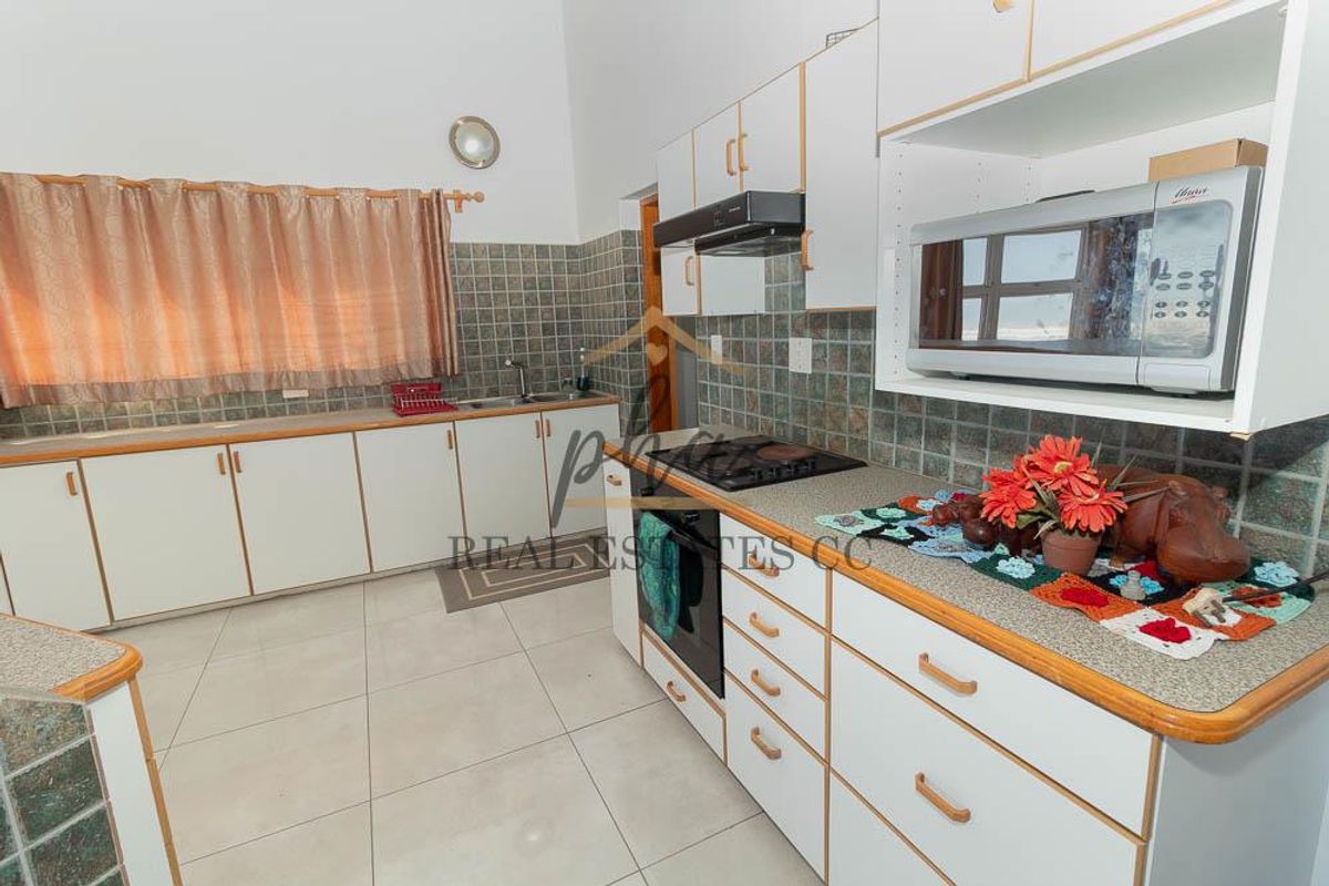 A functional kitchen featuring white cabinetry, tiled backsplash, built-in oven, extractor fan, and tiled flooring.