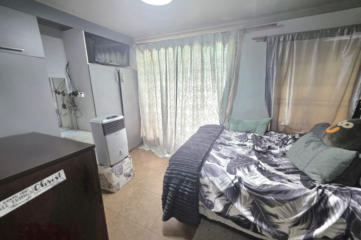 A bedroom featuring tiled flooring and a built-in cupboard, currently showing signs of wear and exposed electrical wiring.