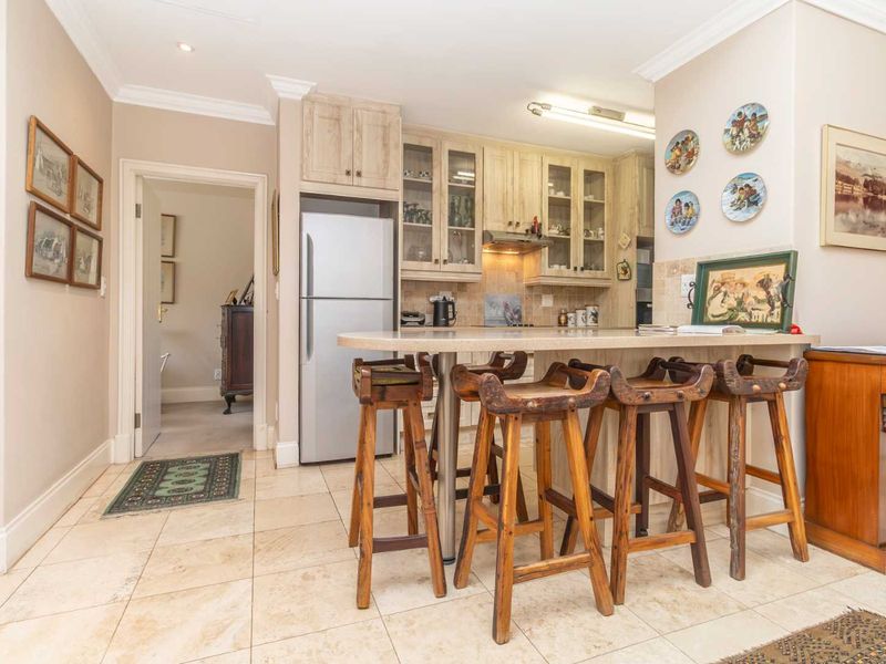 A functional kitchen featuring light-toned built-in cabinetry, a stone breakfast bar, and tiled flooring, providing a practical space for daily meal preparation.