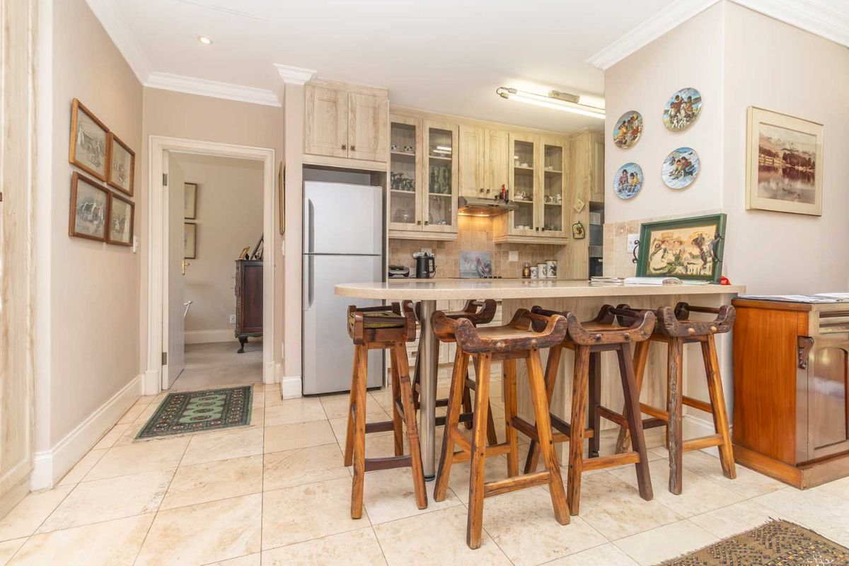 A functional kitchen featuring light-toned built-in cabinetry, a stone breakfast bar, and tiled flooring, providing a practical space for daily meal preparation.