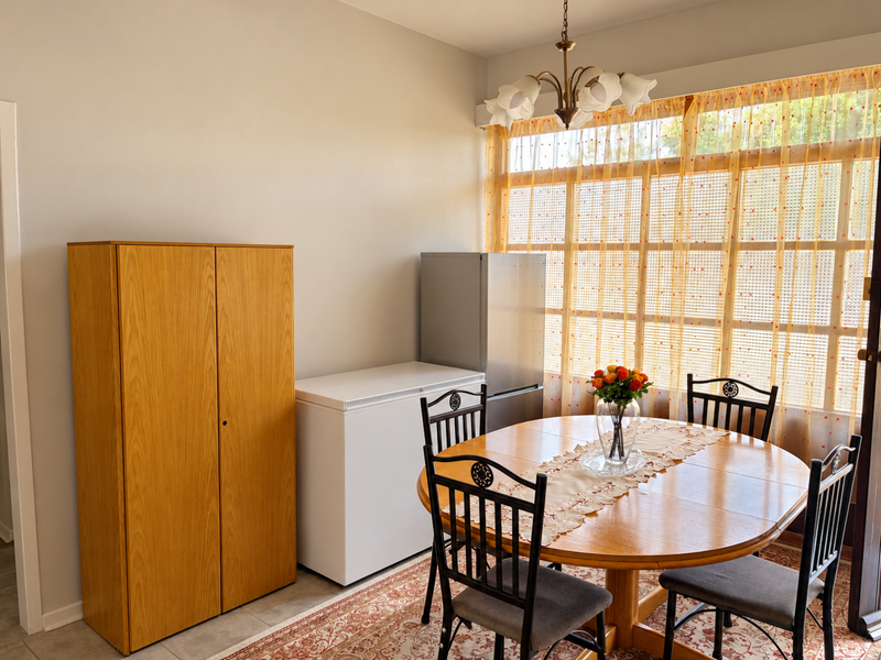 A dining area featuring a large window with natural light and a central ceiling light fixture.