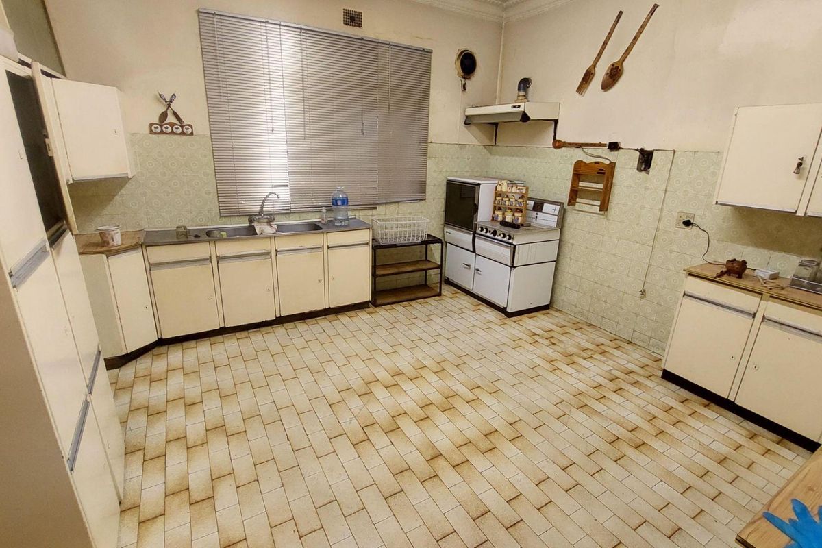 A dated kitchen featuring original cabinetry, tiled flooring, and a built-in stove, offering significant potential for a modern renovation.