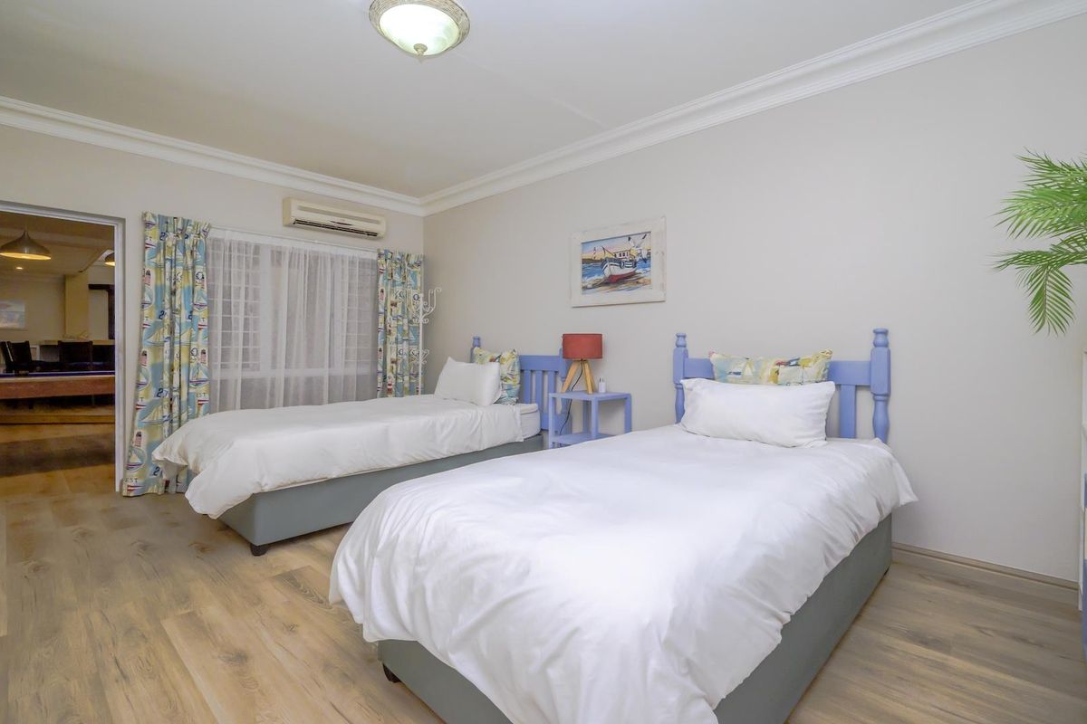 A well-maintained bedroom featuring laminate flooring, crown molding, and a wall-mounted air conditioning unit.