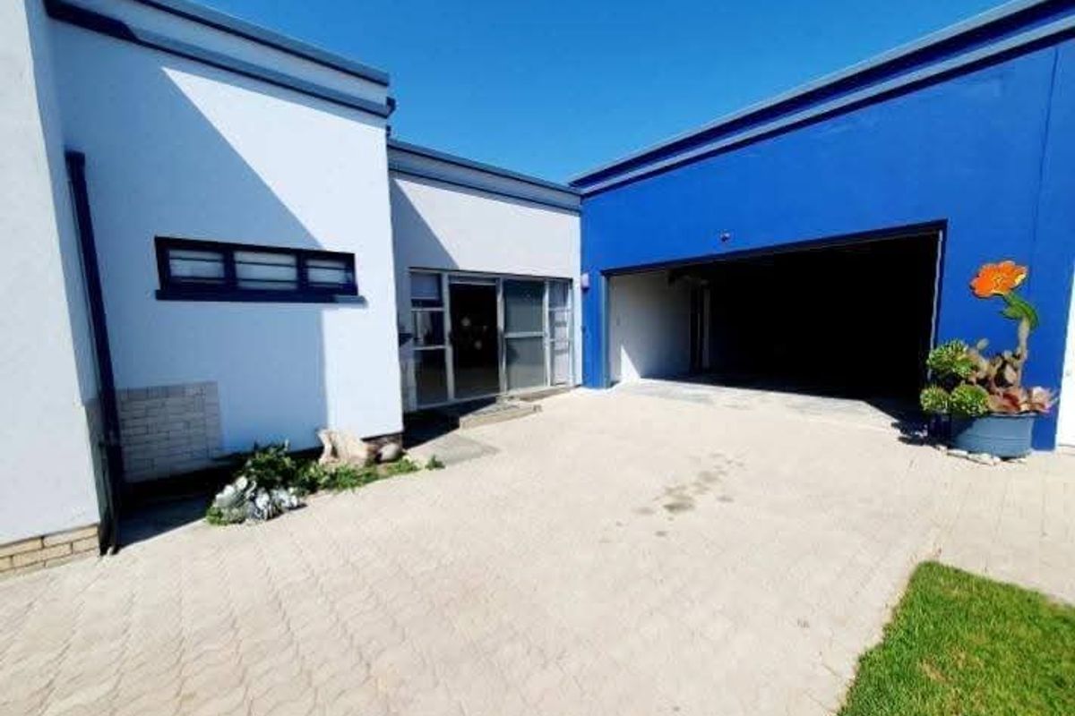 Front exterior view featuring a paved driveway, double garage entrance, and modern white and blue facade with sliding glass door access.