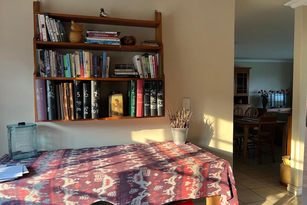 A living area featuring tiled flooring and decorative coving, with a view through to the adjacent dining space.