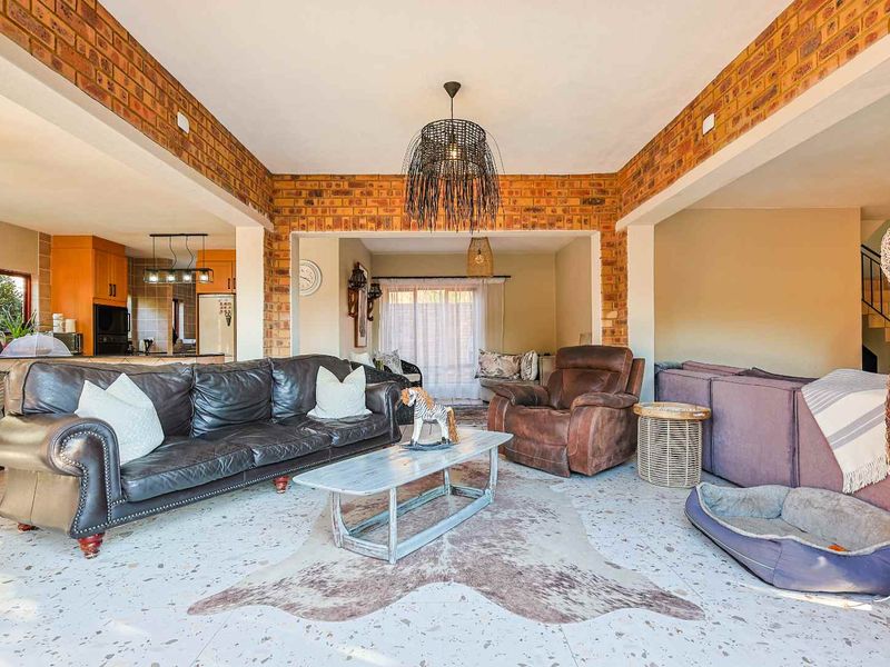 Spacious open-plan living area featuring exposed brick walls, terrazzo flooring, and integrated kitchen space, creating a warm and inviting atmosphere.