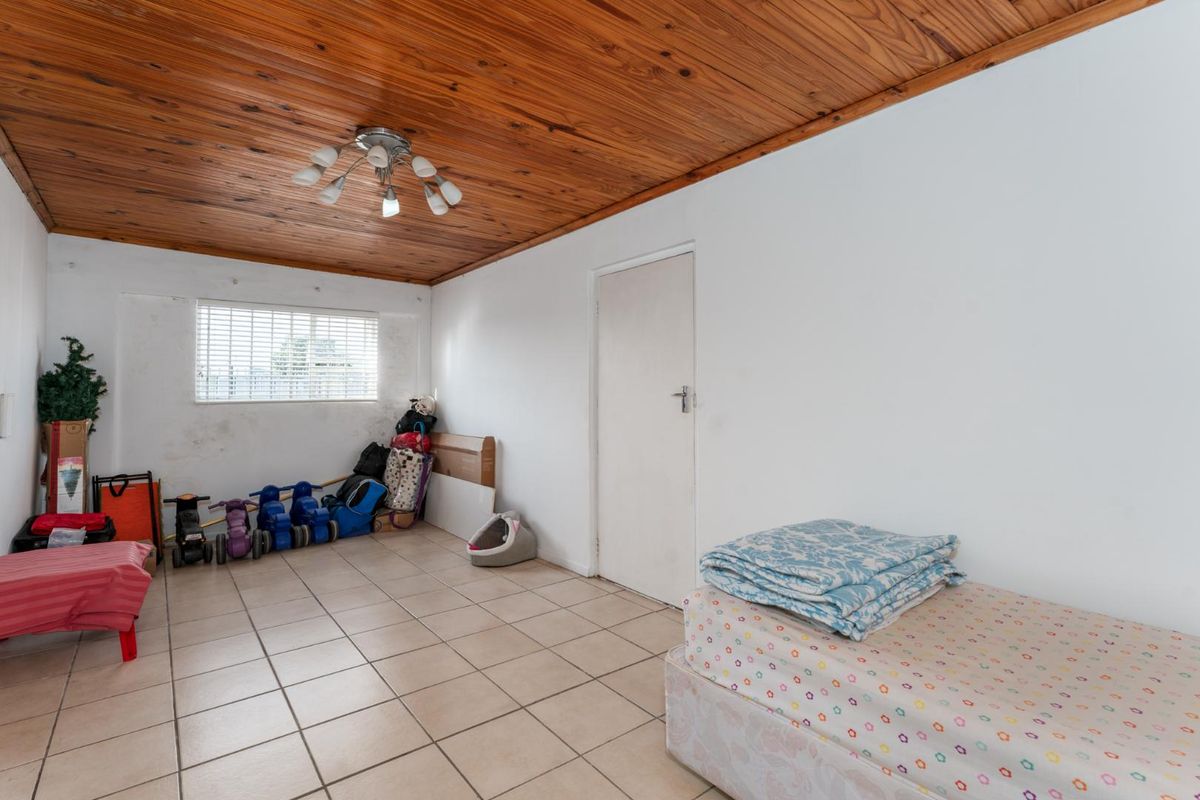 A bedroom featuring ceramic floor tiles and a wooden tongue and groove ceiling, requiring cosmetic updates to the walls.