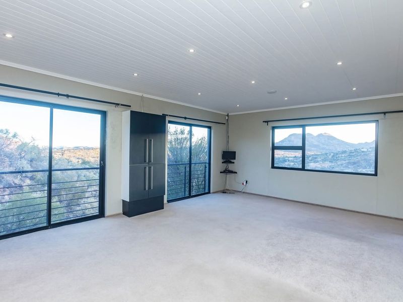 Spacious living area featuring neutral carpeting, recessed downlighting, and large sliding glass doors that offer expansive mountain views.