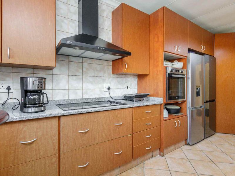A functional kitchen featuring wooden cabinetry, granite countertops, a built-in oven, and a ceramic tile backsplash with tiled flooring.