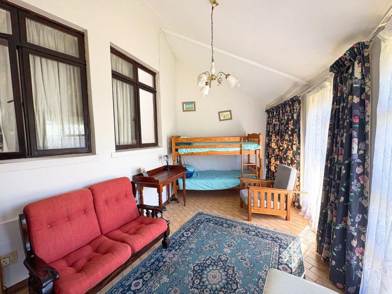 A bedroom featuring tiled flooring, a vaulted ceiling, and large windows that provide natural light.