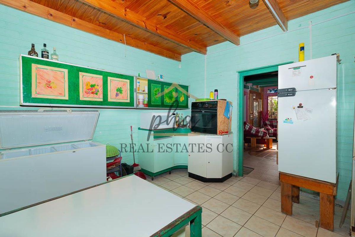 A dated kitchen featuring exposed timber beam ceilings, tiled flooring, and built-in cabinetry with an integrated oven.