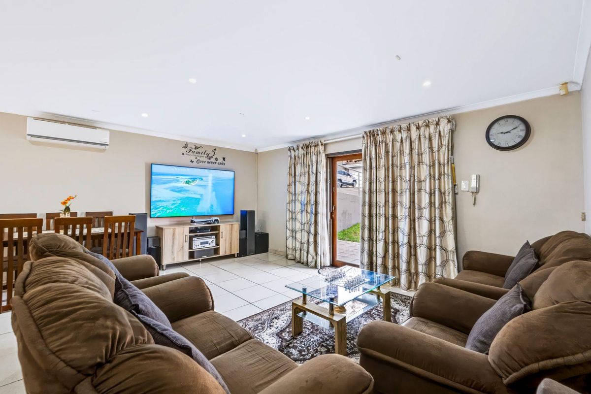 A well-maintained living room featuring tiled flooring, recessed lighting, and a split-system air conditioner, with direct access to the outdoor area via a sliding door.