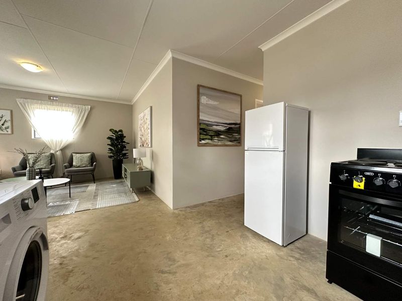 Open-plan living area featuring polished concrete floors, coved ceilings, and a functional kitchen space with a built-in oven and hob.