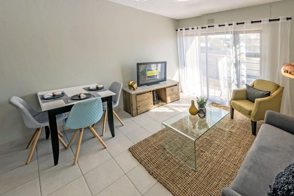 Bright open-plan living and dining area featuring neutral tiled flooring and a large sliding glass door providing access to the outdoor space.