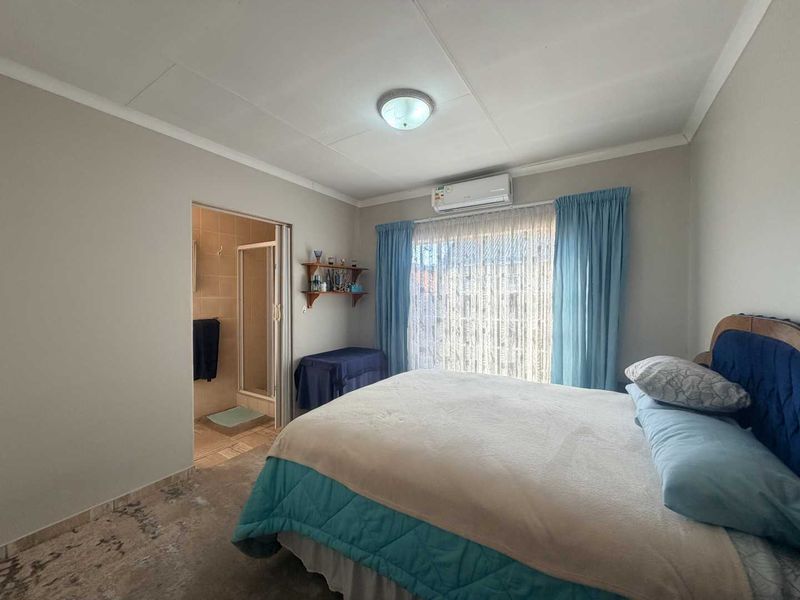 A bedroom featuring tiled flooring, a split-system air conditioner, and an attached en-suite bathroom.