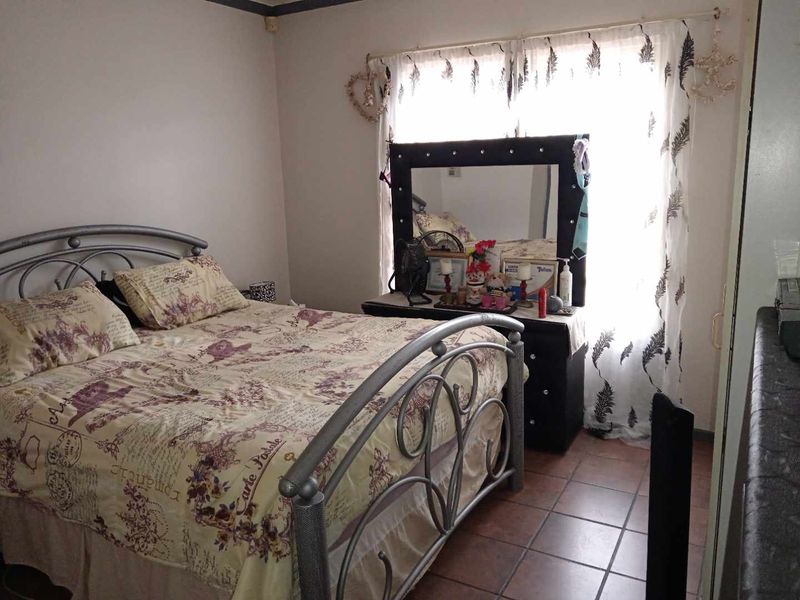 A bedroom featuring tiled flooring and a window with a curtain rod.
