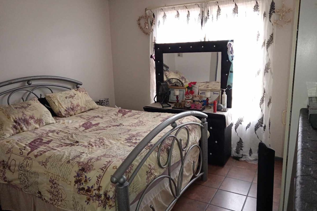 A bedroom featuring tiled flooring and a window with a curtain rod.