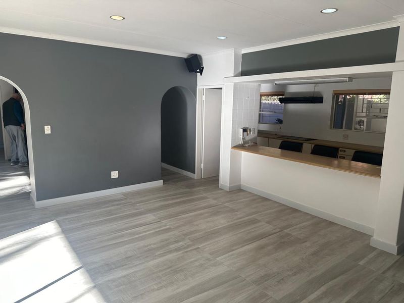 Open plan living area featuring light wood-look laminate flooring, a breakfast bar, and an arched entryway leading to adjacent rooms.