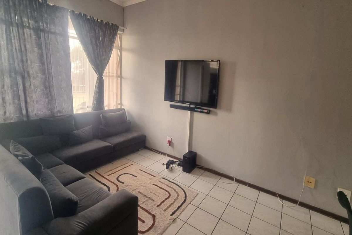 A living room featuring tiled flooring and a wall-mounted television setup with visible cable management.