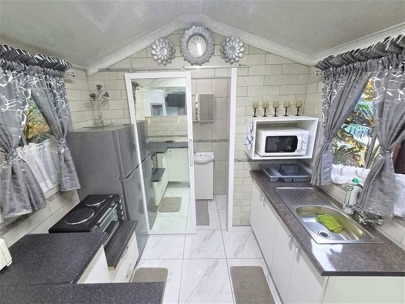 Compact kitchen featuring tiled flooring, subway tile backsplash, laminate countertops, and built-in cabinetry with a functional layout.