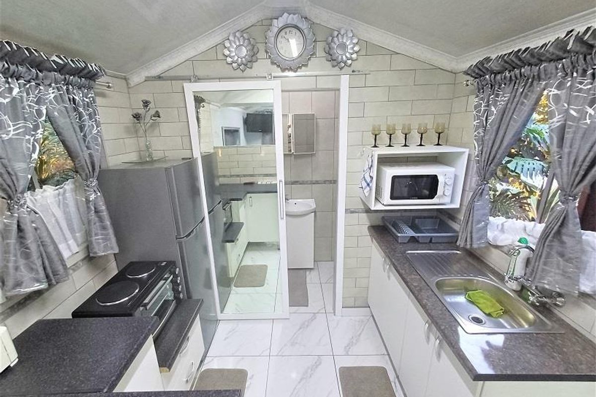 Compact kitchen featuring tiled flooring, subway tile backsplash, laminate countertops, and built-in cabinetry with a functional layout.